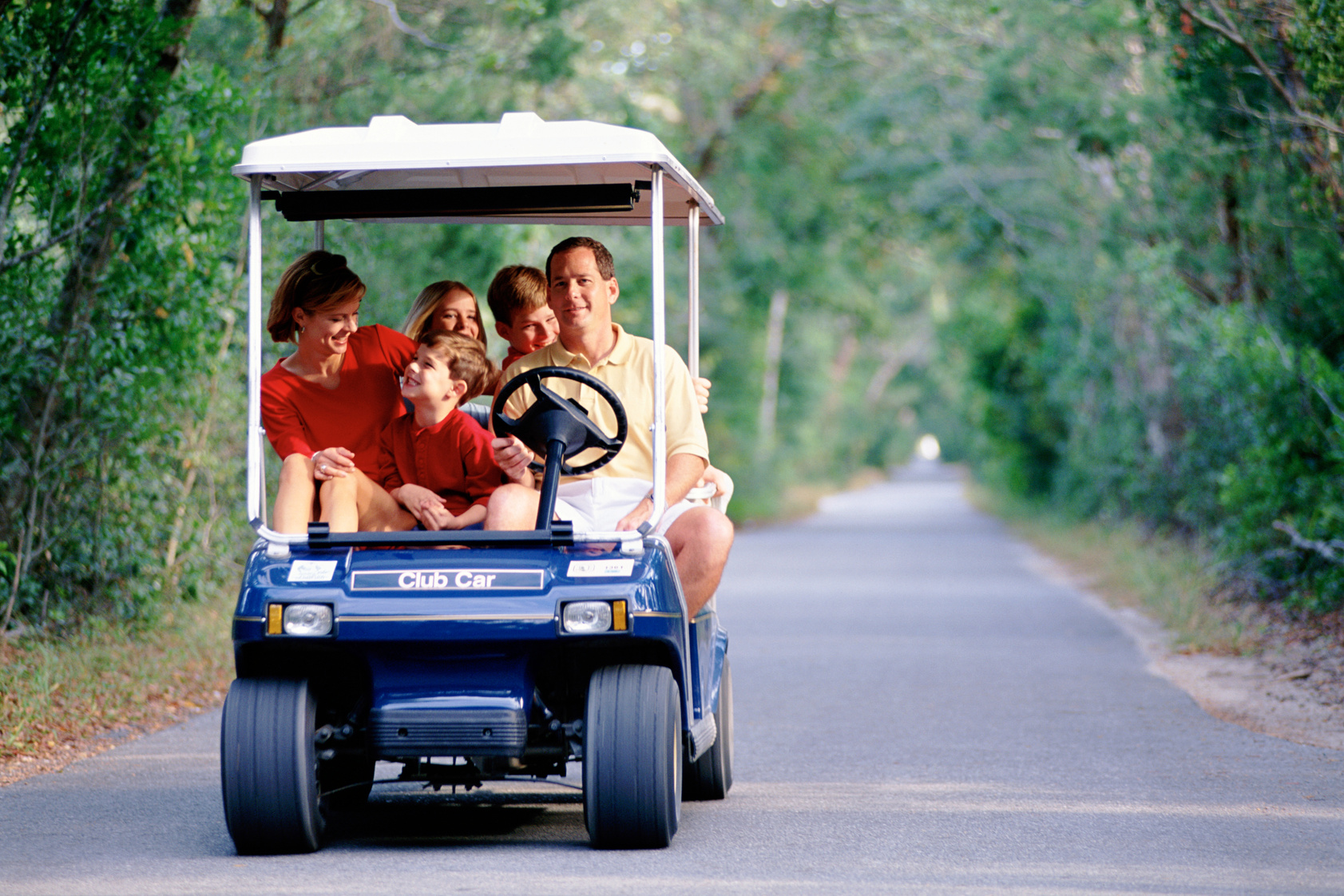 Family riding in a golf cart on a road